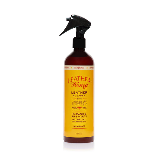 Leather Honey Leather Cleaner bottle and cleaning cloth on a wooden surface, showcasing the product for leather cleaning.