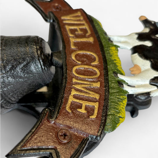 Rustic cast iron cow welcome bell sign for farmhouse door decor, featuring Iron & Blossom branding and vintage farmyard charm