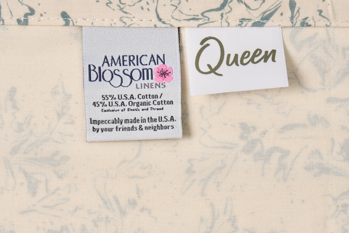 Blue botanical print cotton bed sheet set from American Blossom Linens with natural background and size labels.