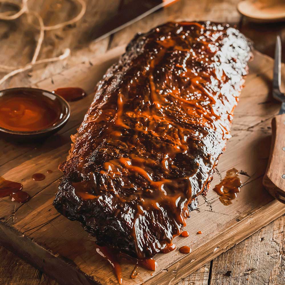 Limited edition Bourbon Barrel Smoked Ribs from Pig of the Month BBQ, showcasing glazed, tender ribs with smoked bourbon flavor.