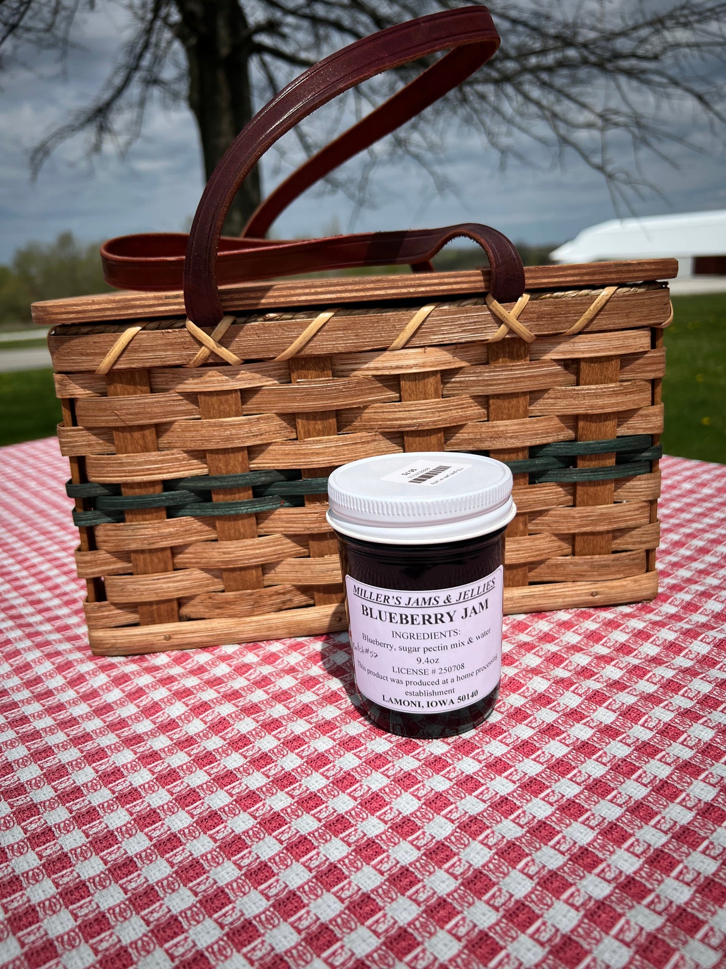 Amish Country Store Miller's Blueberry Jam jar with blue label and fresh blueberries around, showcasing authentic Amish jam.