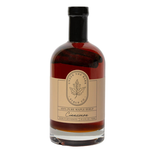 25 oz bottle of cinnamon maple syrup from Under The Bark Syrup Co, featuring rich cinnamon and maple flavors in a glass bottle.