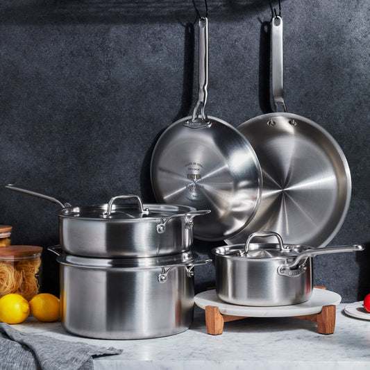 Heritage Steel Eater 8-piece cookware core set with stainless steel pots and pans, arranged on a kitchen countertop.