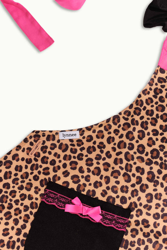 Pink leopard Lynnee apron with adjustable straps, featuring a bold leopard print design, perfect for cooking or baking.