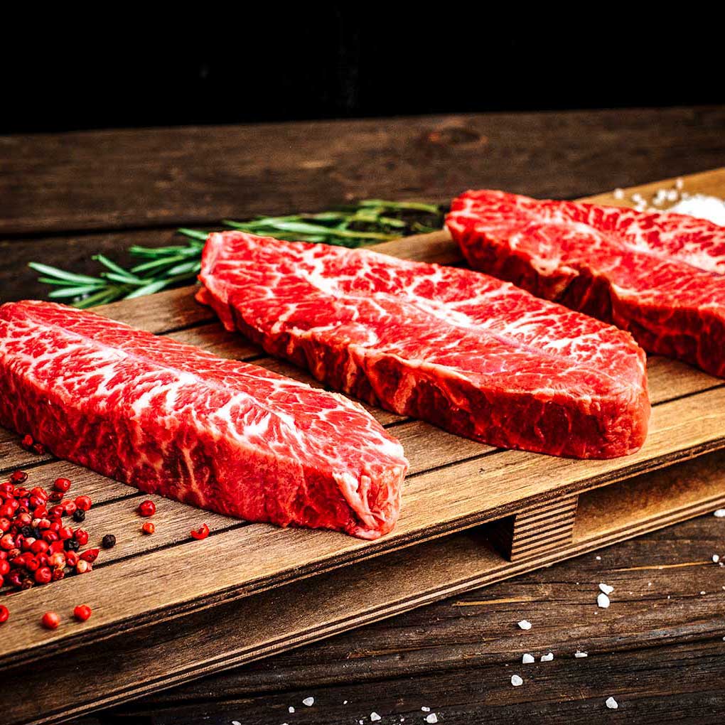 Grass-fed Prime NY Strip Steak from Pig of the Month BBQ, showcasing a juicy, thick cut of organic beef ready for grilling.