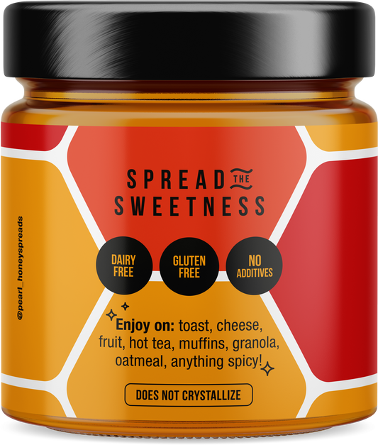 Jar of Pearl Honey Spreads spicy creamed honey with a golden hue and spicy red pepper flakes visible inside.