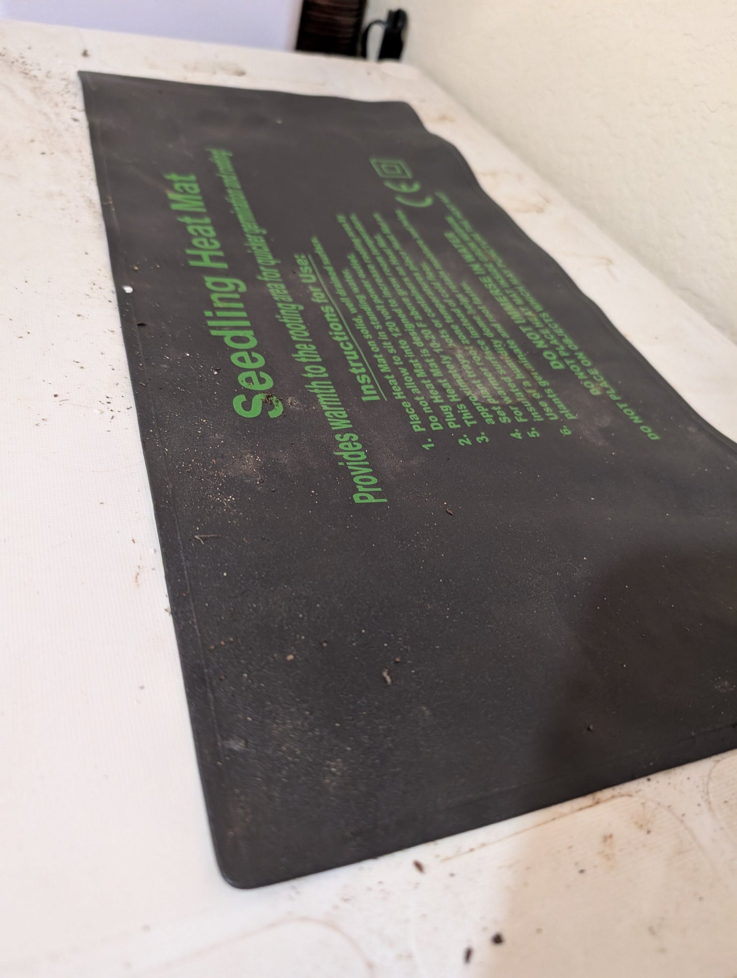 Hasty Roots seedling heat mat for gardening supplies, showing a close-up of the black mat with textured surface for plant propagation.