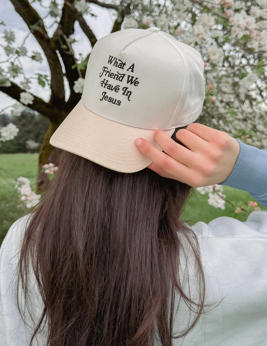 Elevated Faith trucker hat featuring the phrase "What a Friend in Jesus" embroidered on the front in black and white.