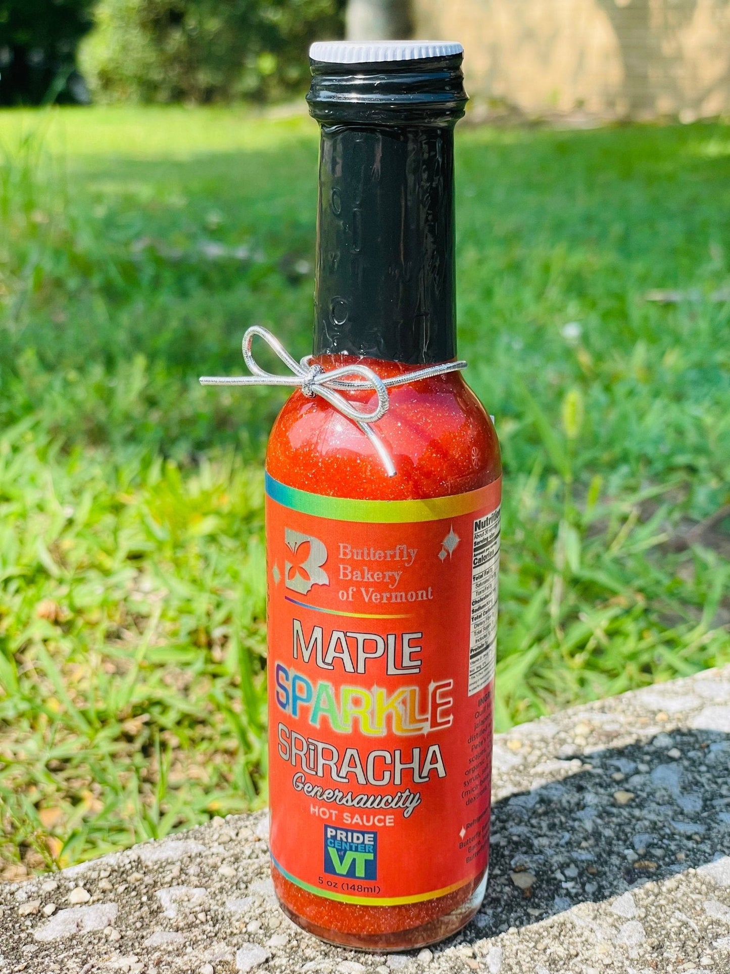 Vermont Maple Sparkle Sriracha hot sauce by Butterfly Bakery in a 5 oz bottle, featuring vibrant red chili and maple flavor details.