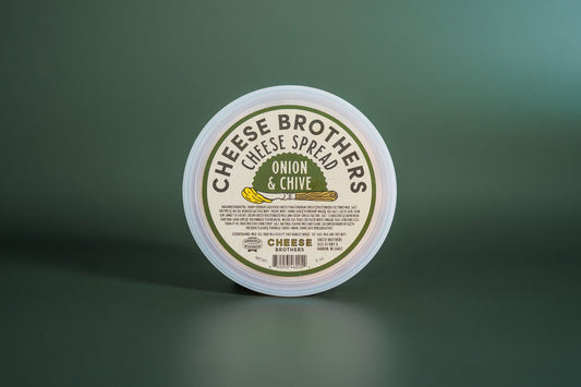 Creamy Onion and Chive Cheese Spread by Cheese Brothers, Inc., with visible herbs and smooth texture in a jar.