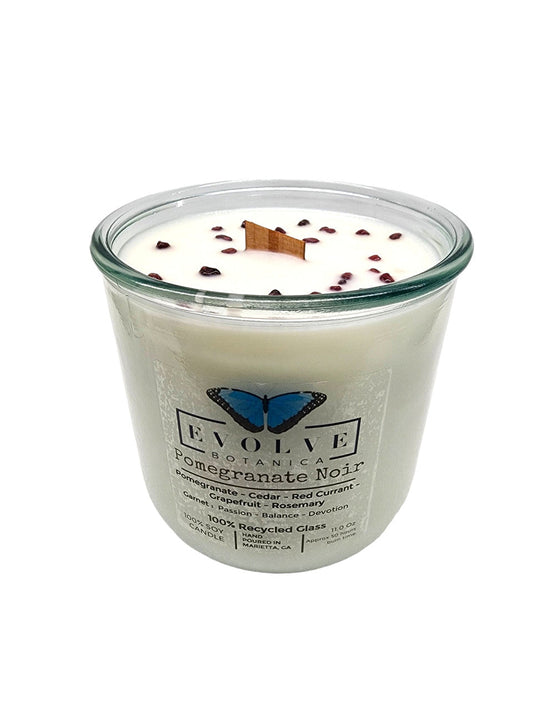 Evolve Botanica Rocks Candle with Pomegranate Noir scent, featuring a wood wick, garnet gemstone, and soy wax in a decorative jar.