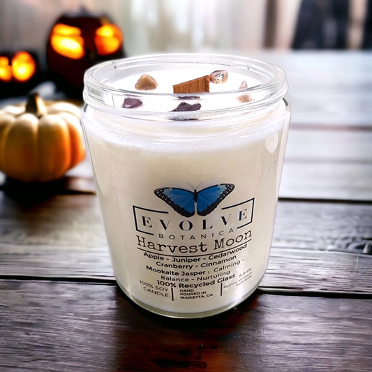 Evolve Botanica 9oz jam jar soy candle with harvest moon scent and mookite crystal, featuring natural wood wick for cozy ambiance.