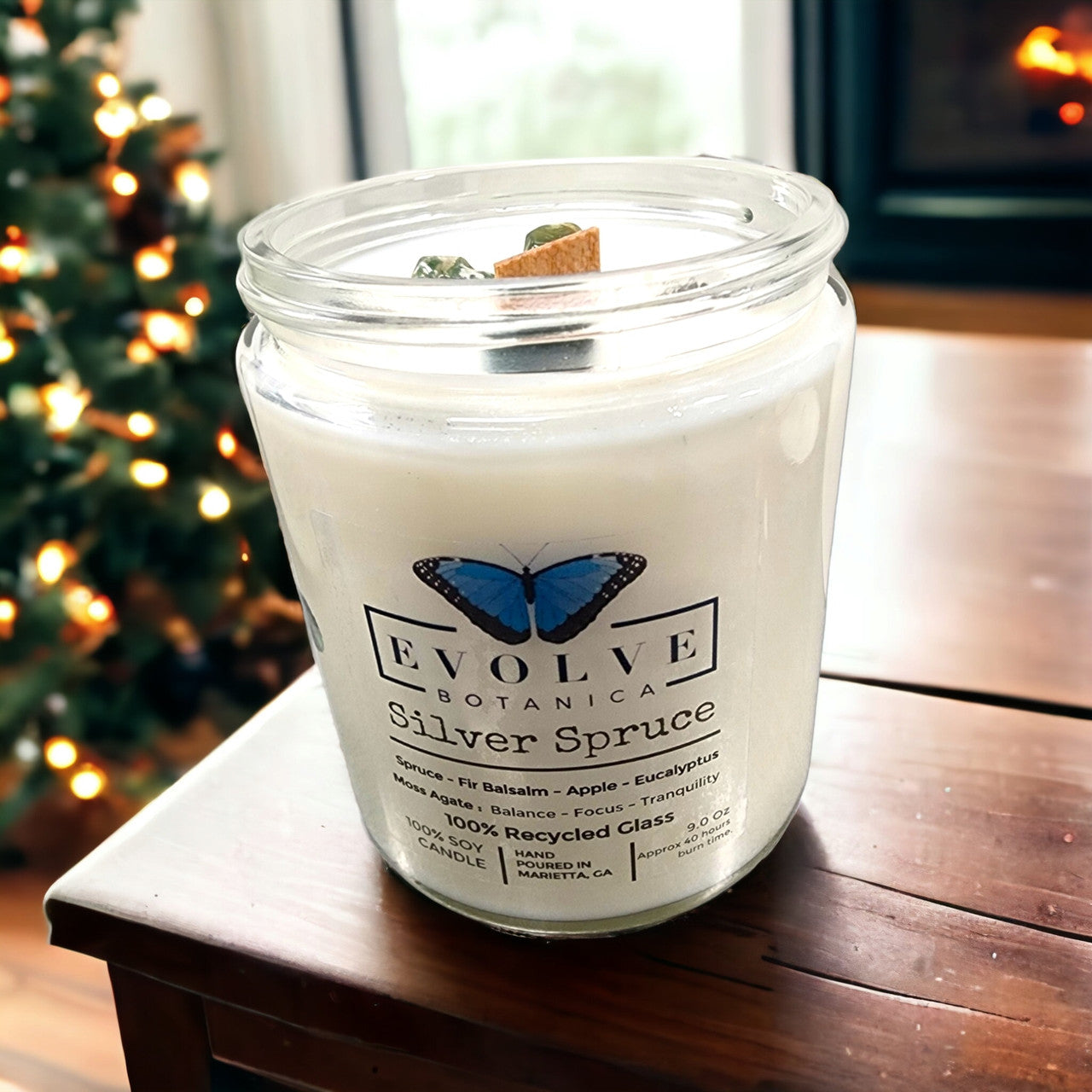 Evolve Botanica 9oz jar soy candle with silver spruce scent, moss agate crystal, natural wood wick, in classic jam jar.