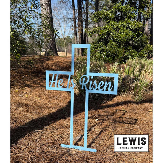 Pastel blue He Is Risen Cross metal yard and garden sign by Lewis Design Company, outdoor Easter patio and garden art.