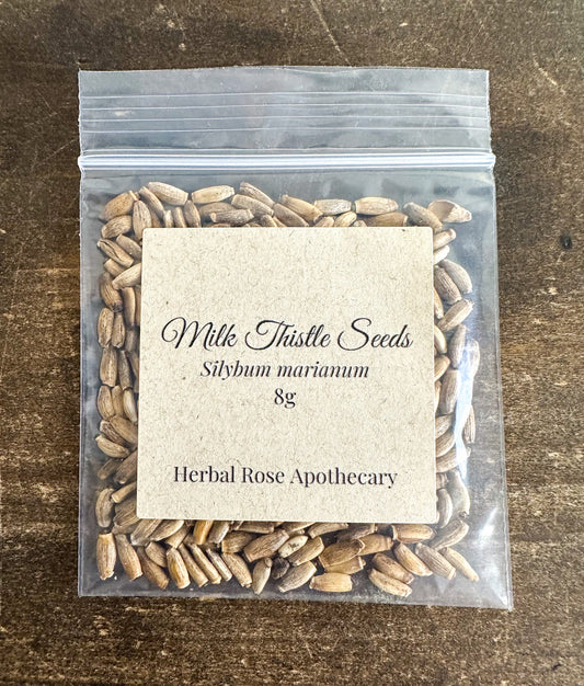 Dried herbal milk thistle seeds in an 8g package from HerbalRoseApothecary, showing small, light brown seeds in a clear container.