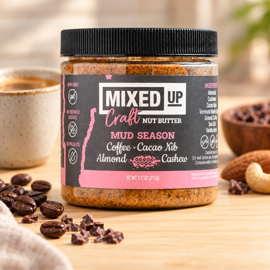 Creamy "Mud Season" nut butter by Mixed Up Foods with cacao nibs and coffee, served in a jar on a rustic background.