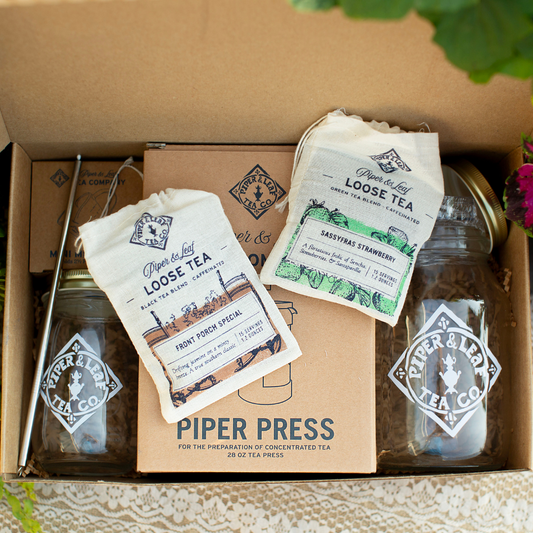 Piper Press Brew Kit from Piper and Leaf Tea Co. on a porch, featuring tea brewing accessories and a sassy strawberry design.