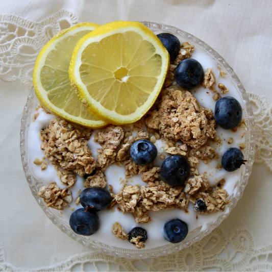 Blueberry Lemon Granola by Rooted Living in a bowl with blueberries and lemon slices, showcasing a crunchy, healthy breakfast option.