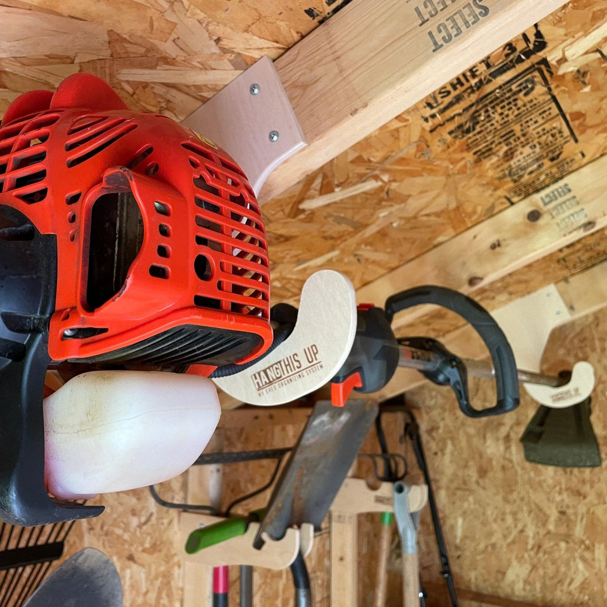 Ceiling-mounted weed wacker rack by HangThis Up, outdoor shed organizer with hooks for storing weed eaters and garden tools.