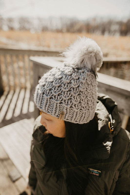 Gray Merino Wool Knit Hat with Faux Fur Pom Pom by Woolly Bear Knits, featuring a cozy wool hat with a plush faux fur pom pom.