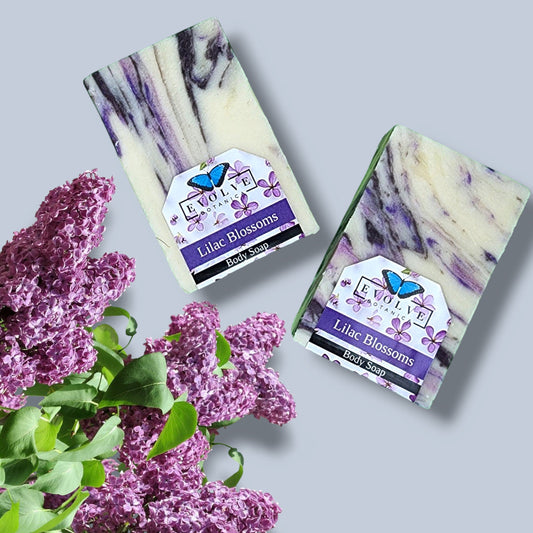 Evolve Botanica seasonal soap with lilac blossoms, featuring a pastel purple soap bar adorned with dried lilac flowers.