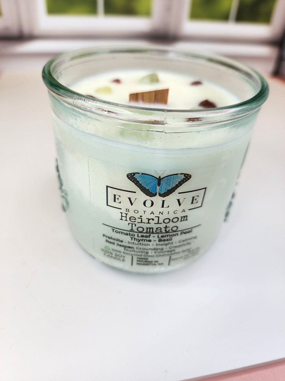 Evolve Botanica Rocks Candle Heirloom Tomato soy candle with wood wick, prehnite, and red jasper stones on a neutral background.