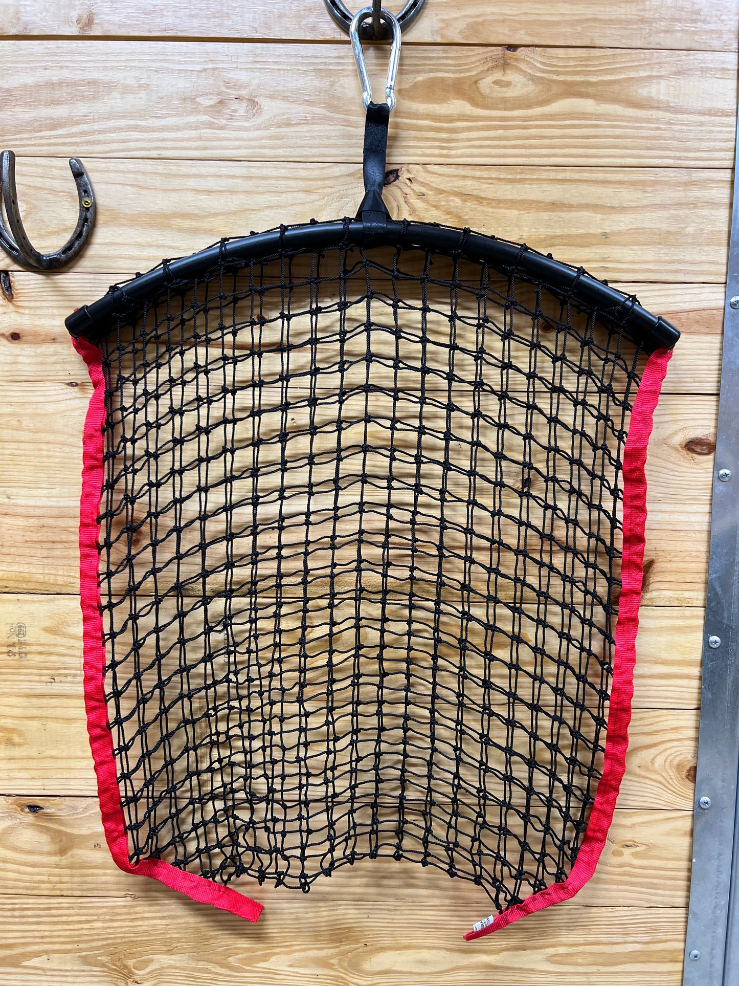 Red regular haynet from Haylo Haynets, LLC with tightly woven mesh for secure hay storage and easy feeding.