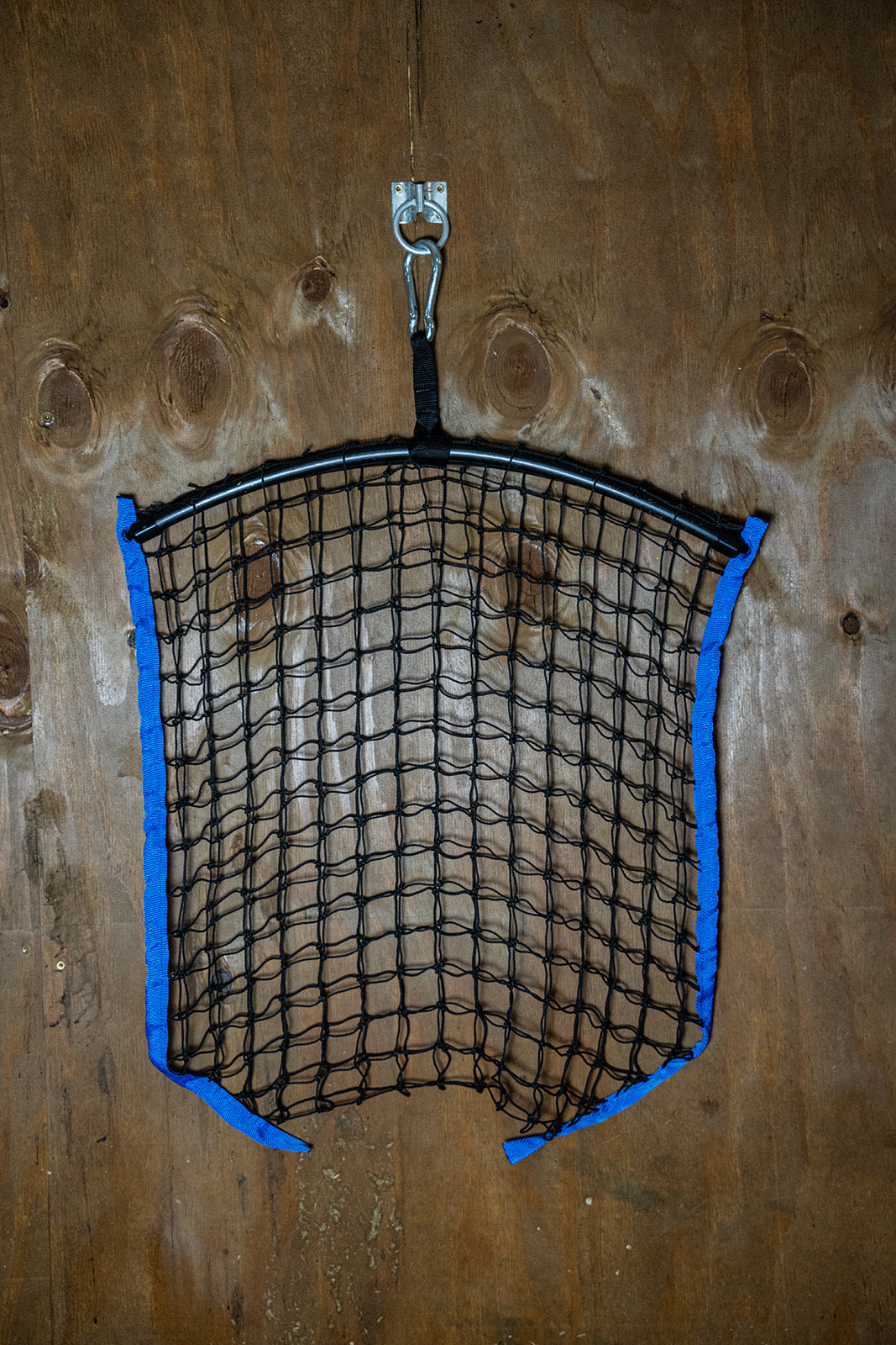 Blue regular haynet by Haylo Haynets, LLC showing a sturdy net filled with hay for livestock feeding.