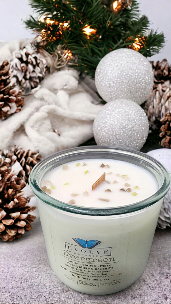 Evergreen soy candle by Evolve Botanica with wood wick, Peridot and Smoky Quartz gemstones, showcasing a lush green candle with gemstones.