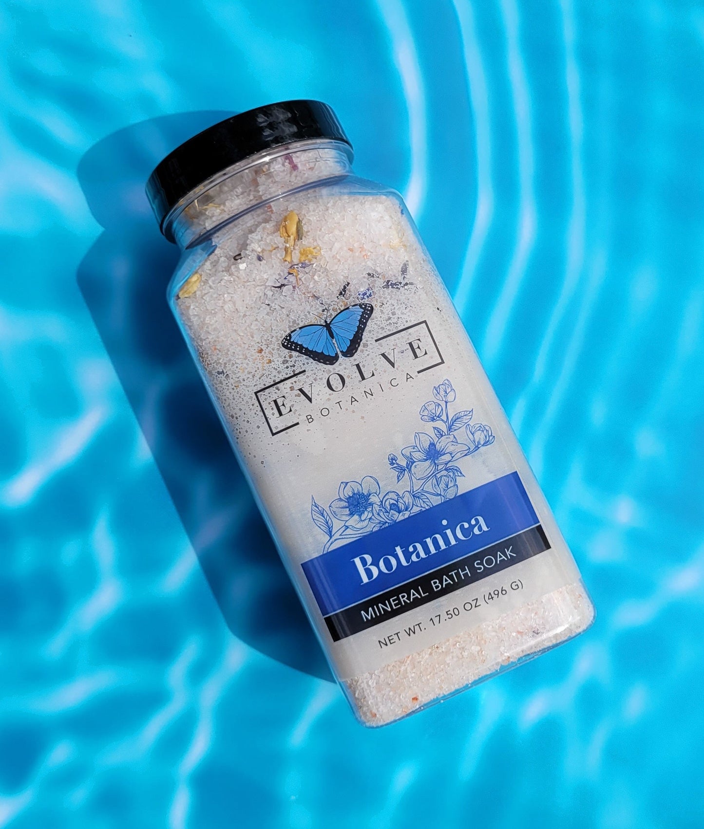 Evolve Botanica Mineral Soak bath salt in a clear jar with a scoop, featuring colorful mineral crystals and botanical accents.