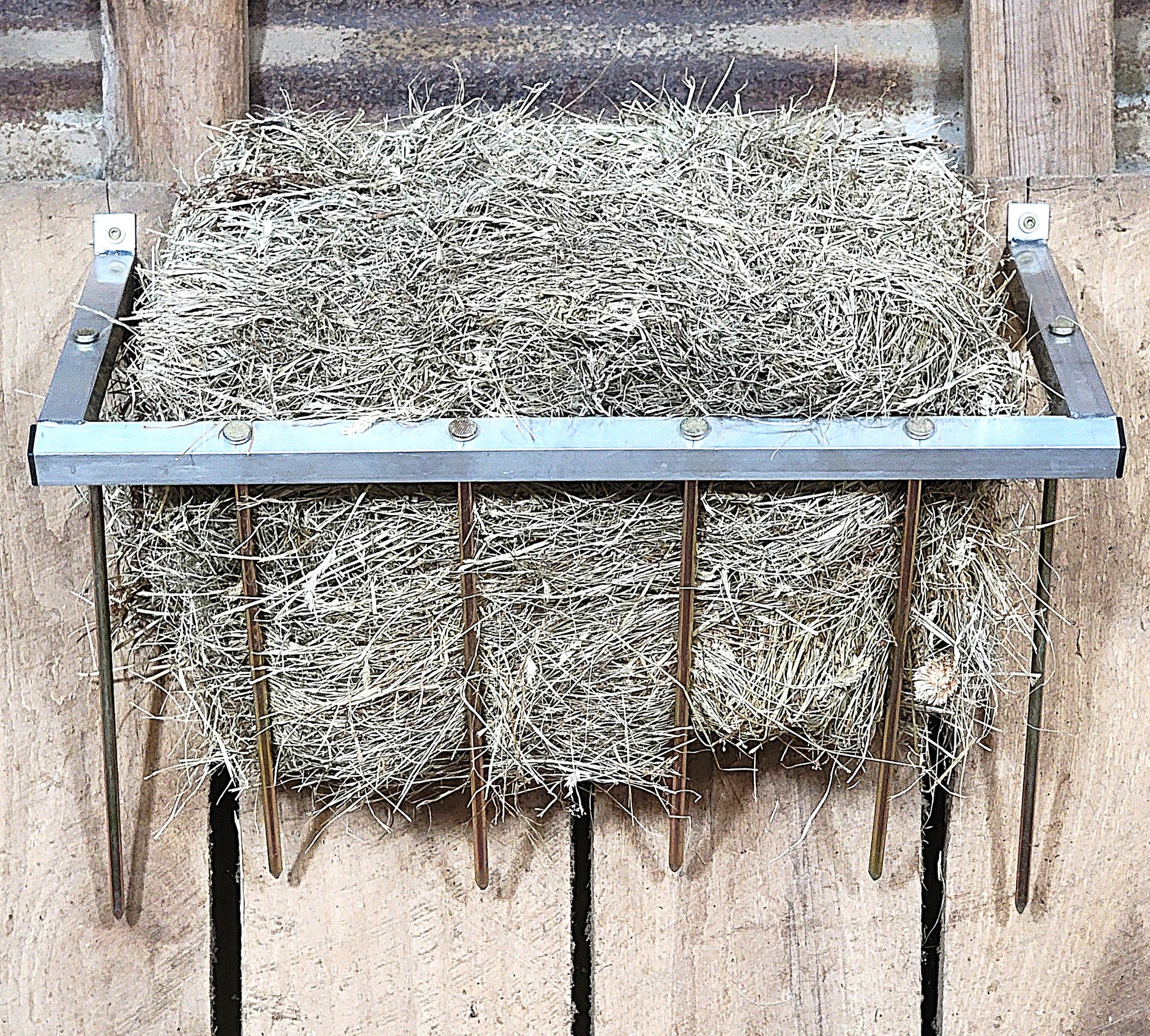 24-inch wall-mounted aluminum sheep and goat hay feeder, suitable for fences, stalls, and pens. Durable USA-made design.