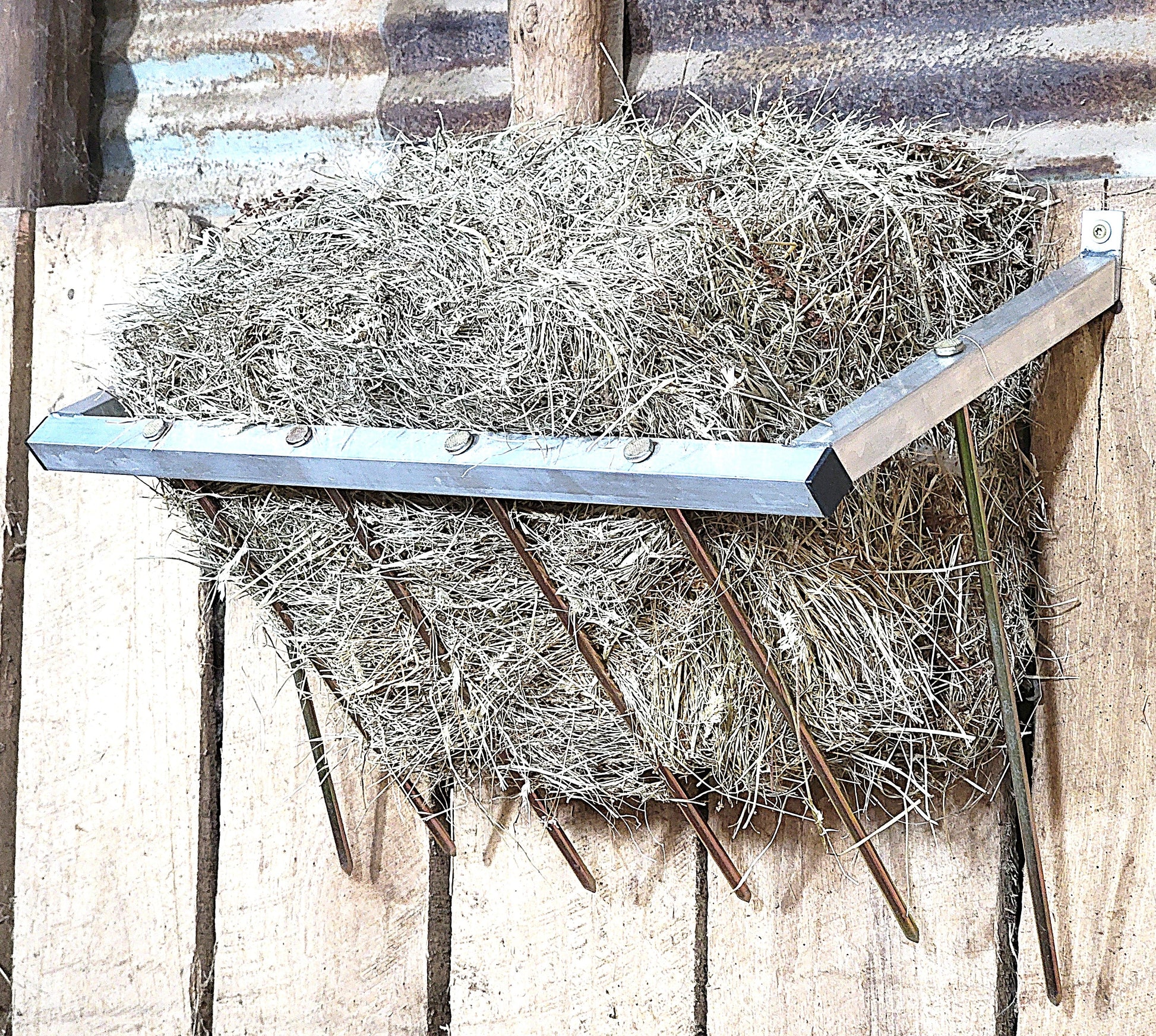 24-inch wall-mounted sheep and goat hay feeder made of USA-made aluminum, designed for fences, stalls, and pens.