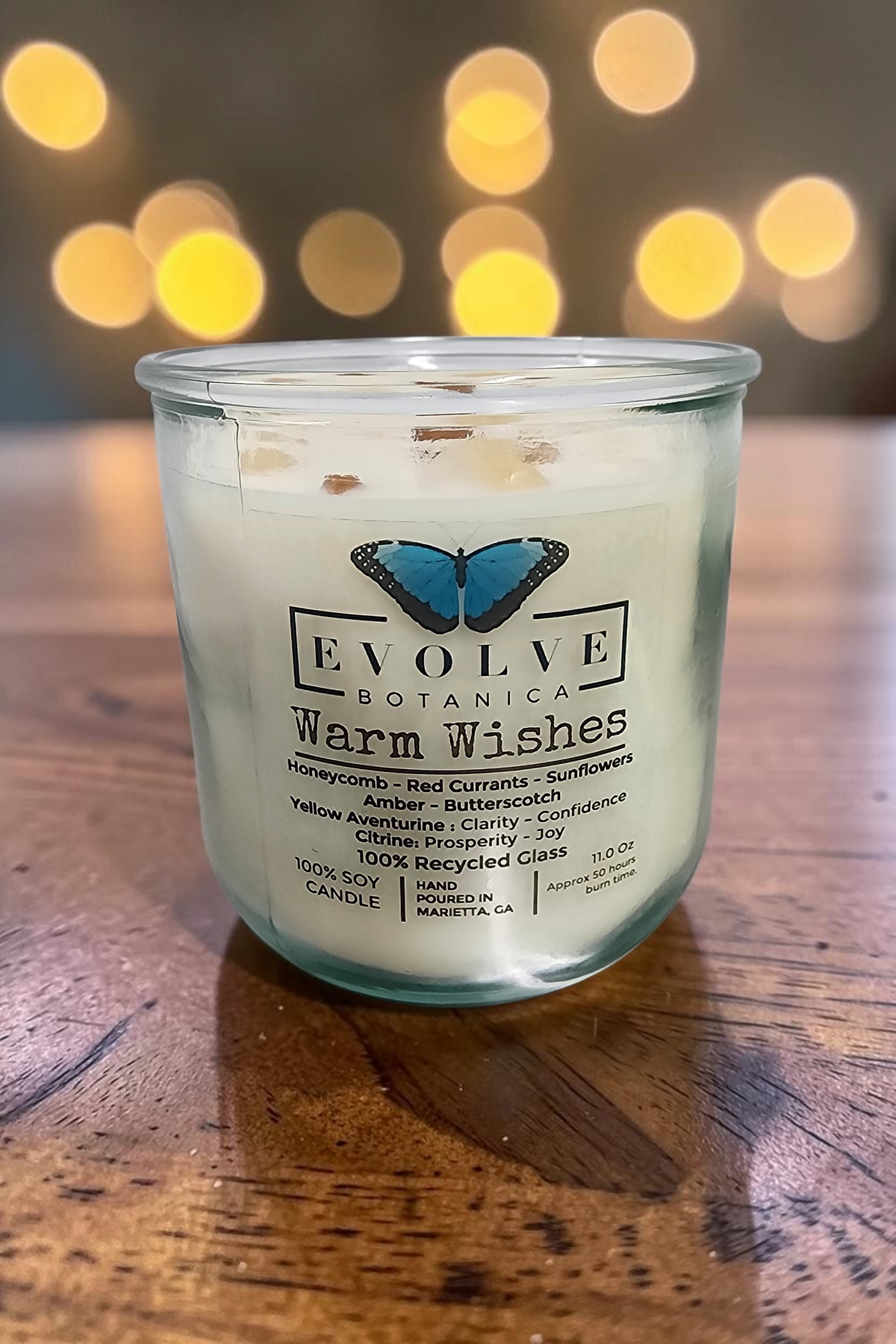 Evolve Botanica Rocks Candle Warm Wishes with wood wick, citrine and aventurine gemstones, soy wax, in a decorative jar.