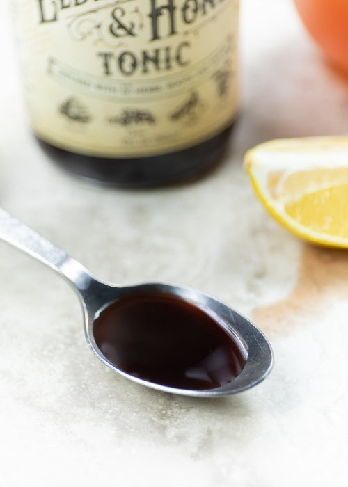 Elderberry and honey tonic bottle from Roots and Leaves LLC, with label showing natural ingredients and vibrant packaging.