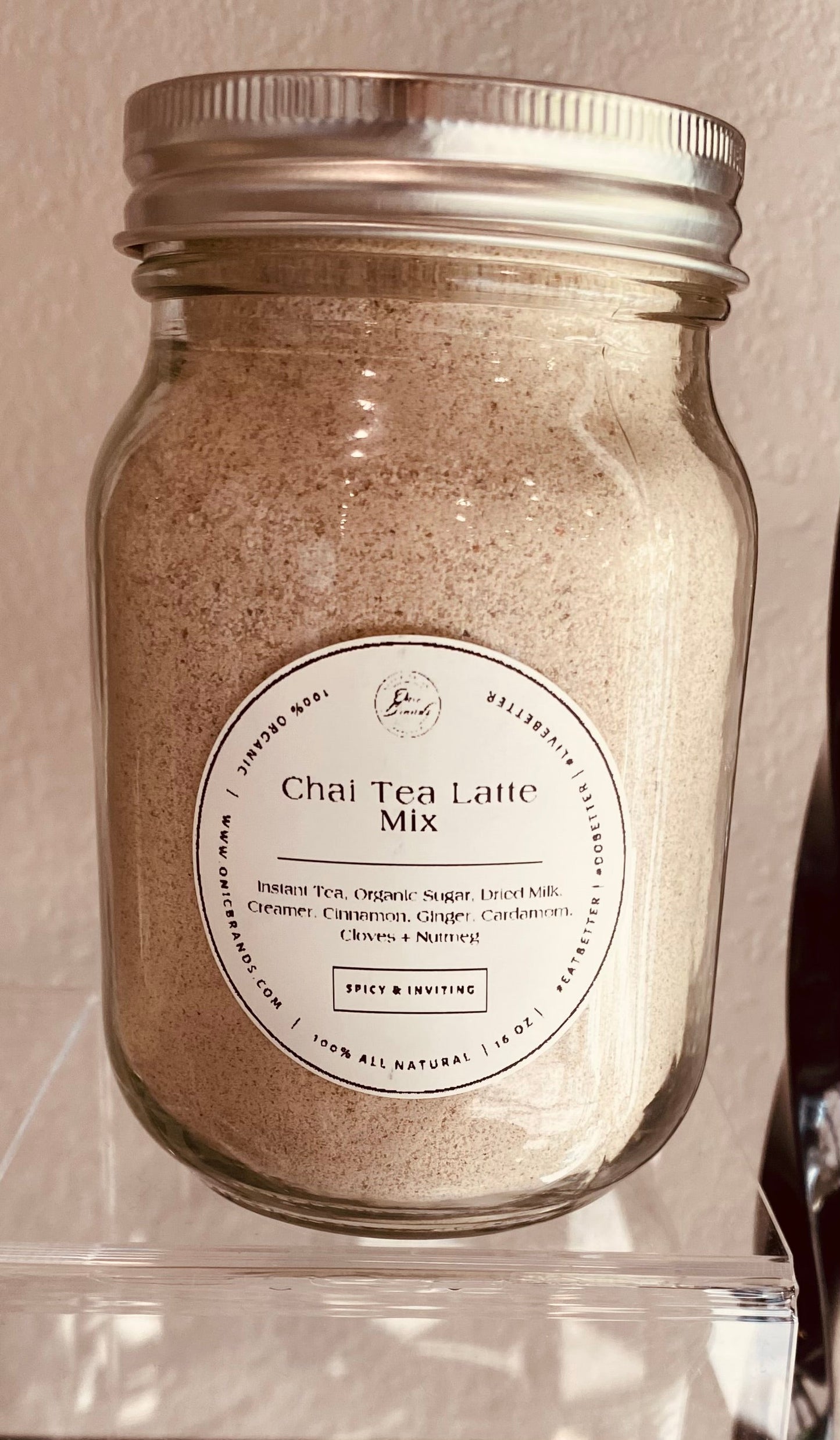 Creamy chai tea latte in a clear glass cup with cinnamon and spice, served hot, by Onic Brands LLC.