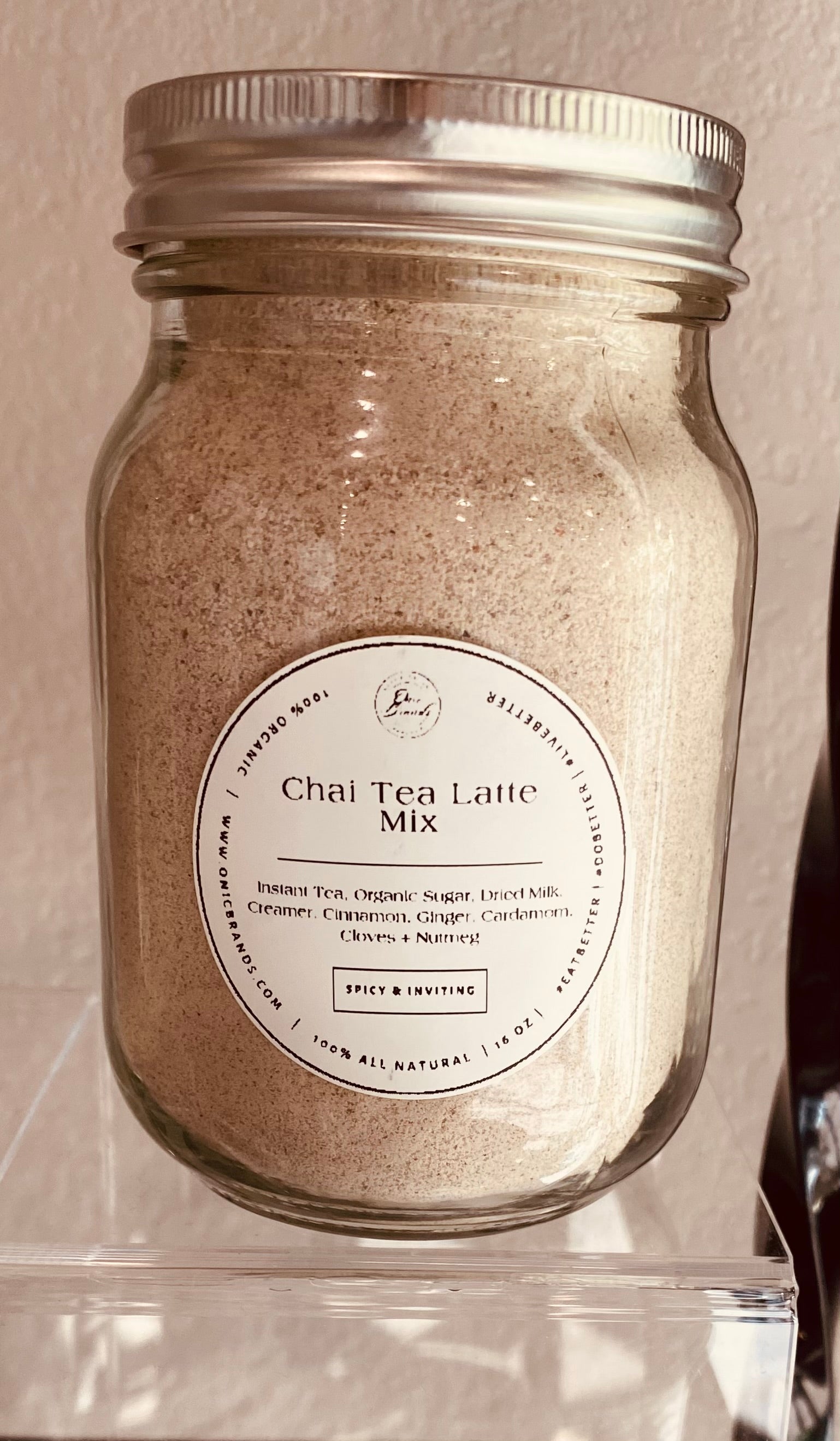 Creamy chai tea latte in a clear glass cup with cinnamon and spice, served hot, by Onic Brands LLC.