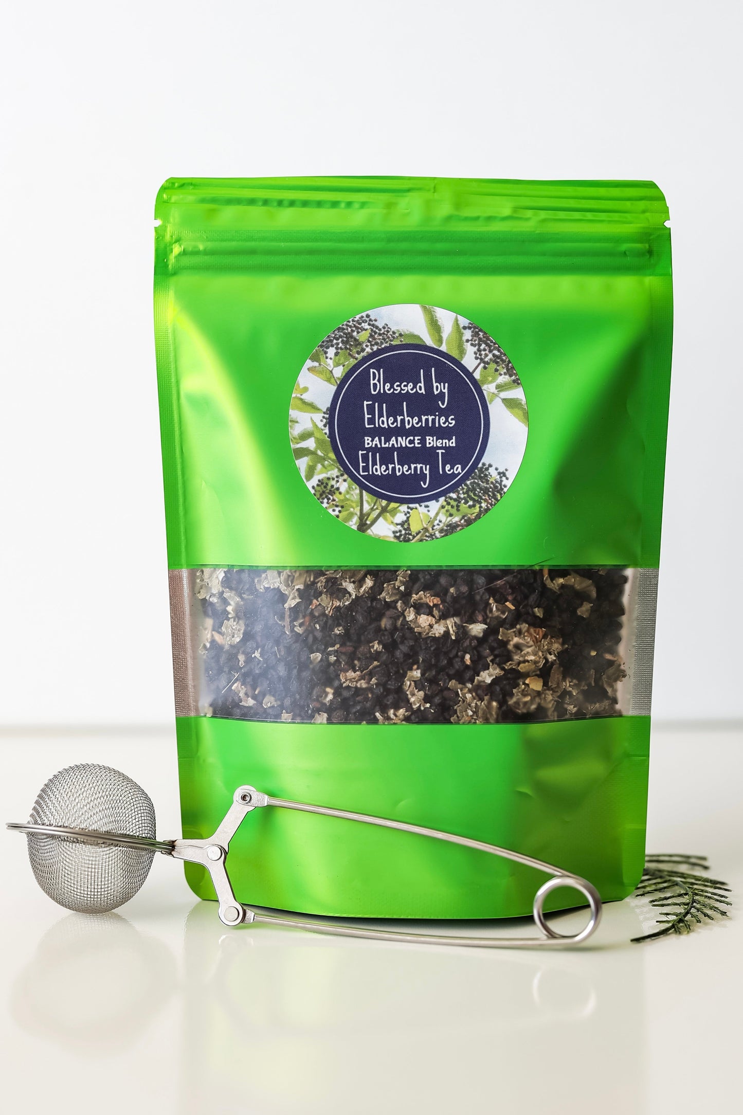 Balance Blend Elderberry tea by Blessed by Elderberries in a clear glass cup with brewed tea and elderberries visible.
