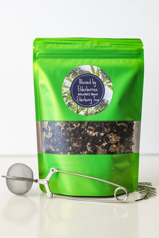 Balance Blend Elderberry tea by Blessed by Elderberries in a clear glass cup with brewed tea and elderberries visible.