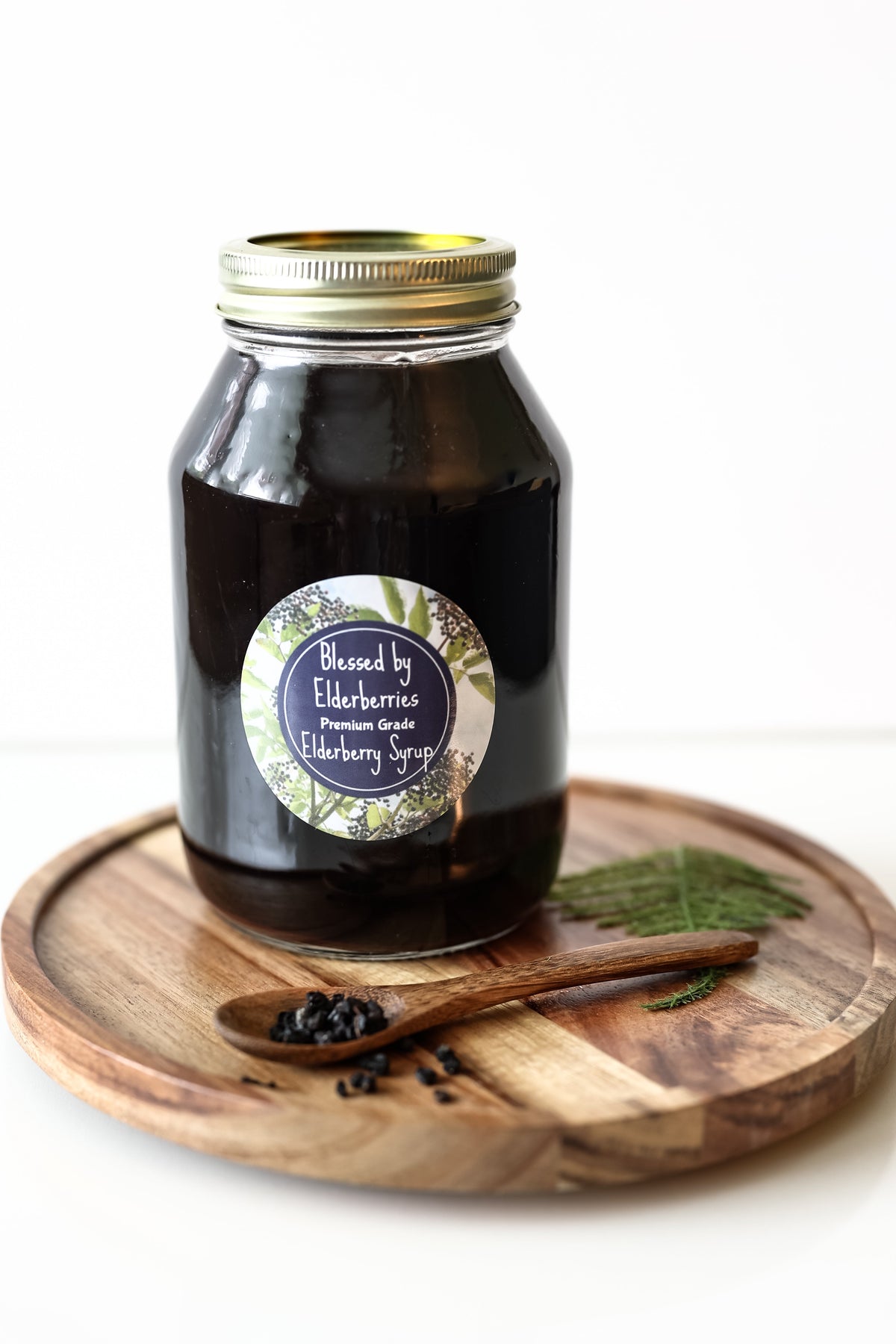 Elderberry syrup bottle from Blessed by Elderberries with fresh elderberries and syrup poured in a glass jar.