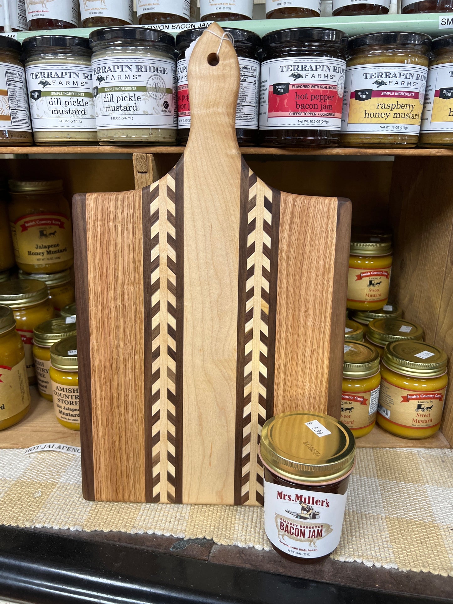 Handmade Amish wheat inlay cutting board made from mixed hardwoods, featuring a paddle shape perfect for kitchen use.