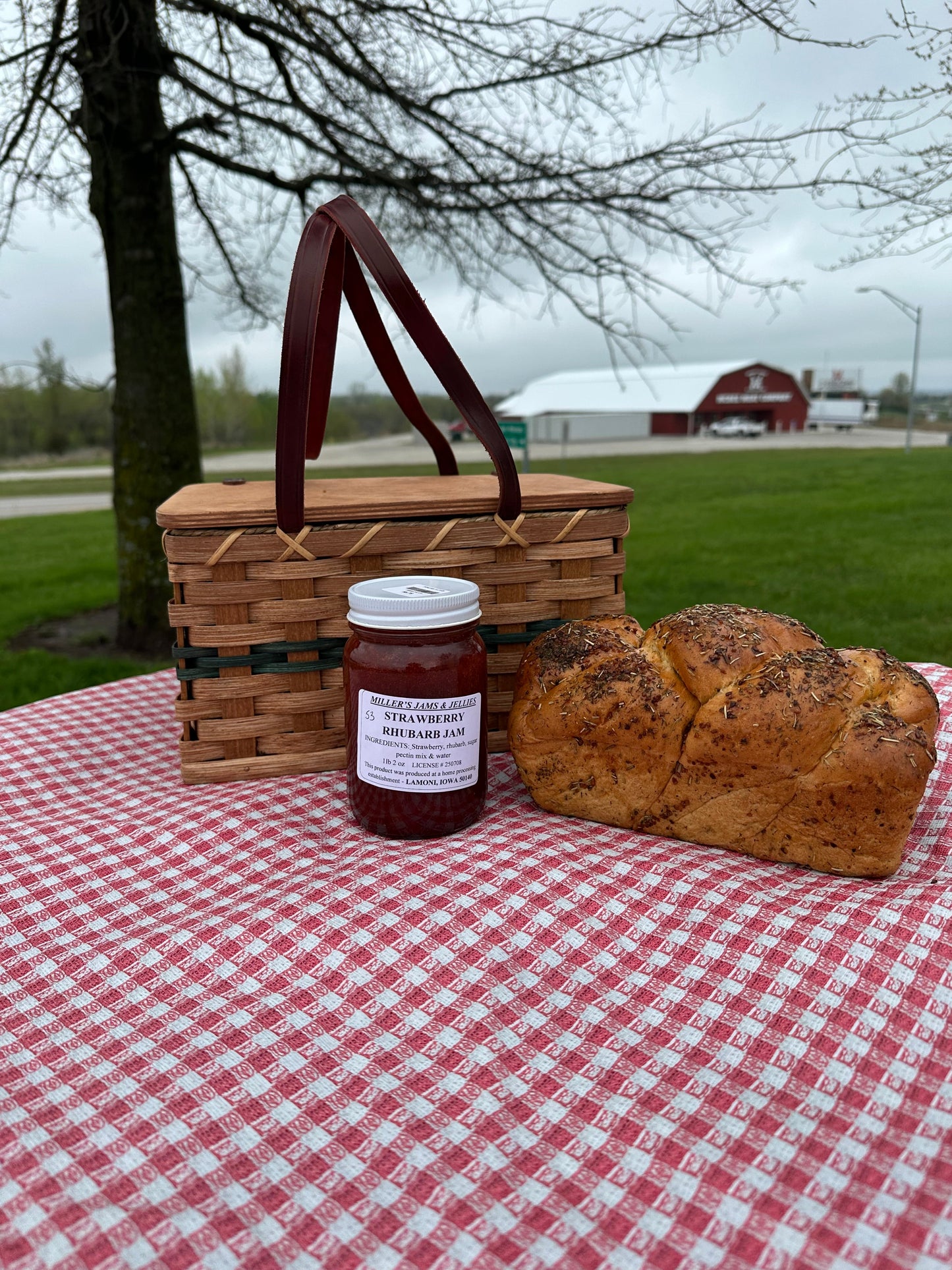 Amish Country Store strawberry rhubarb jam jar featuring a rustic label and fresh strawberries and rhubarb in the background.