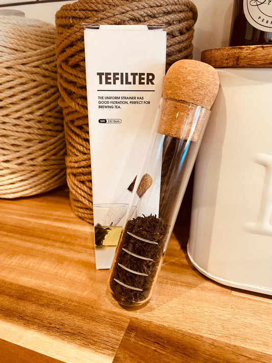 Tea test tube from TEFILTER by Onic Brands LLC, clear glass container with tea leaves inside, used for brewing or testing tea samples.