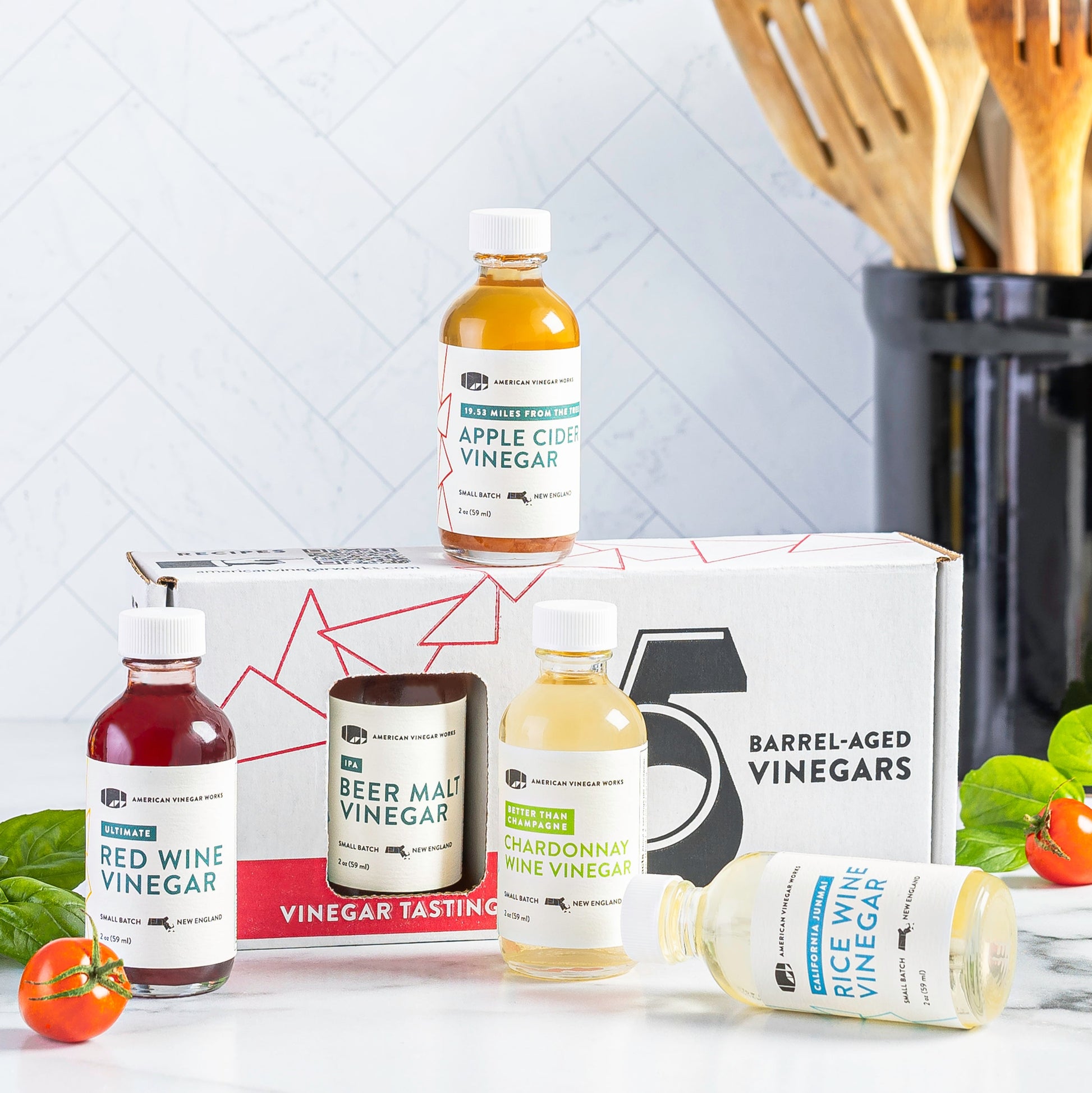 American Vinegar Works Essentials Plus vinegar sampler pack with five barrel-aged vinegar bottles on display.