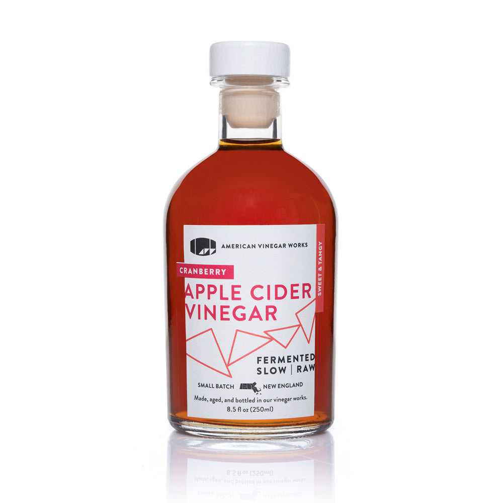 Bottle of American Vinegar Works cranberry apple cider vinegar showing the label and clear glass bottle.
