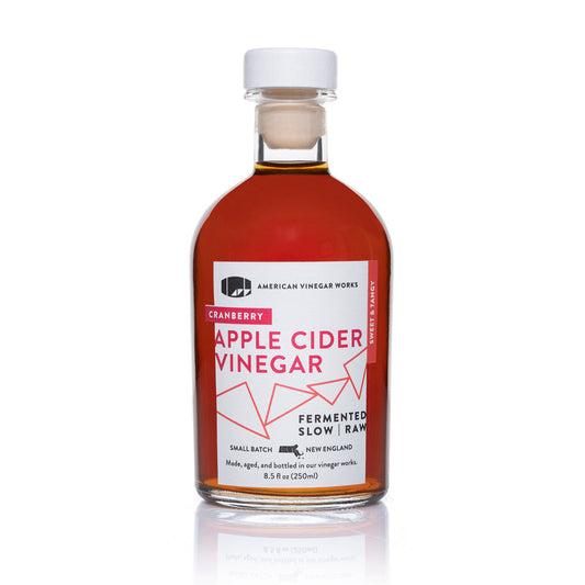 Bottle of American Vinegar Works cranberry apple cider vinegar showing the label and clear glass bottle.