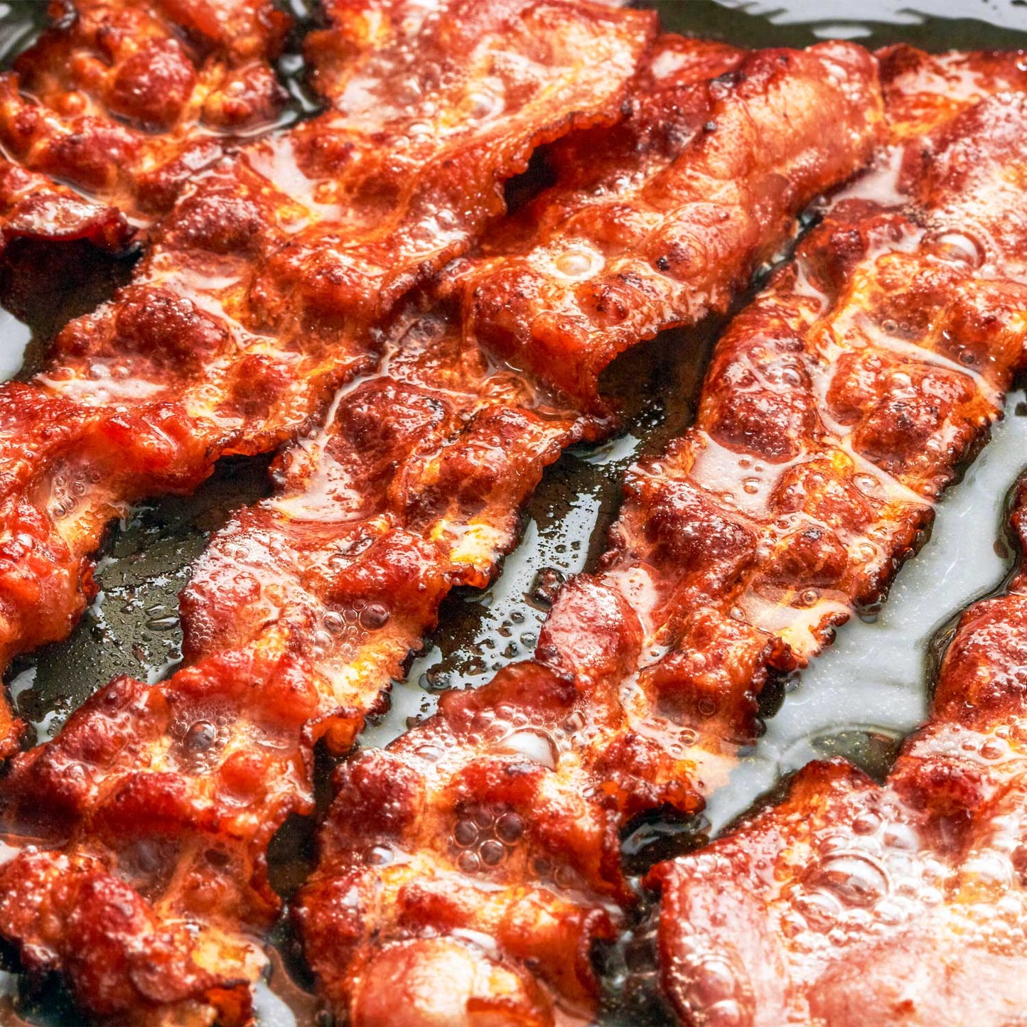 Plate of crispy bacon slices from Pig of the Month BBQ's Bacon Lover's Feast, perfect for bacon enthusiasts.