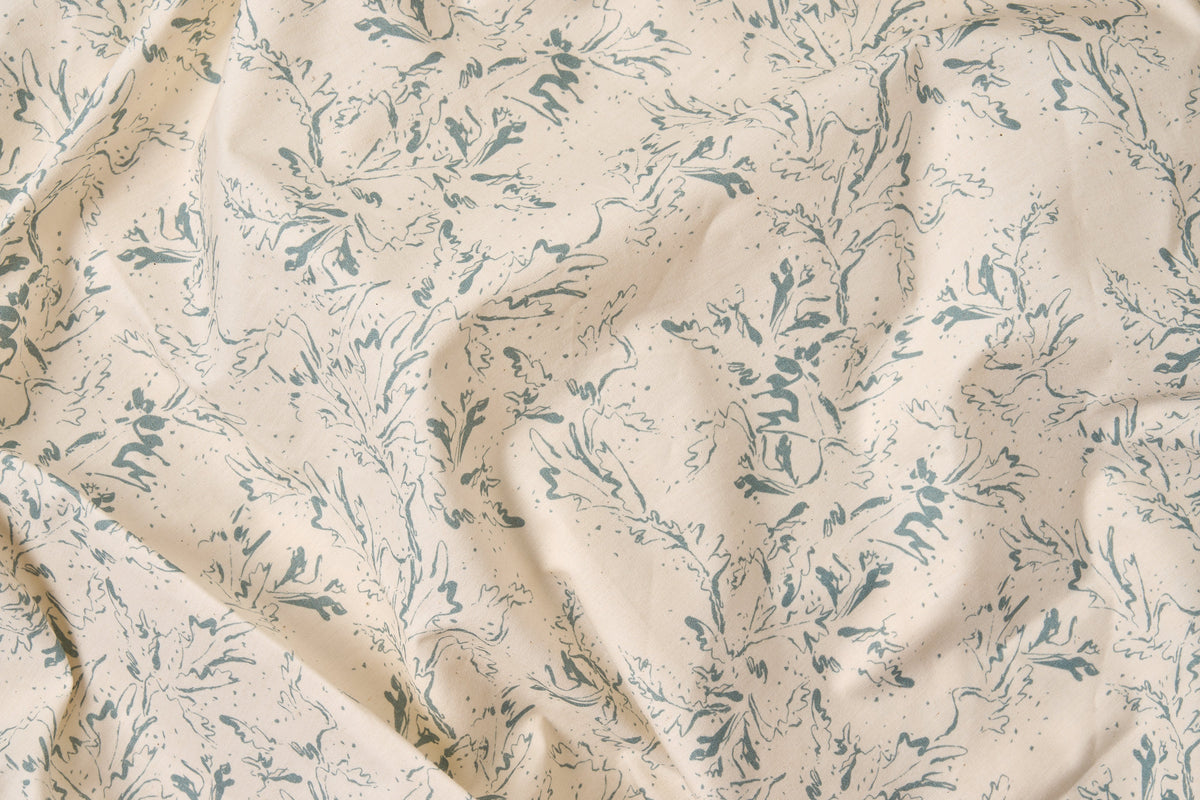 Blue botanical print cotton bed sheet set by American Blossom Linens, close-up of natural background fabric showing detailed design.