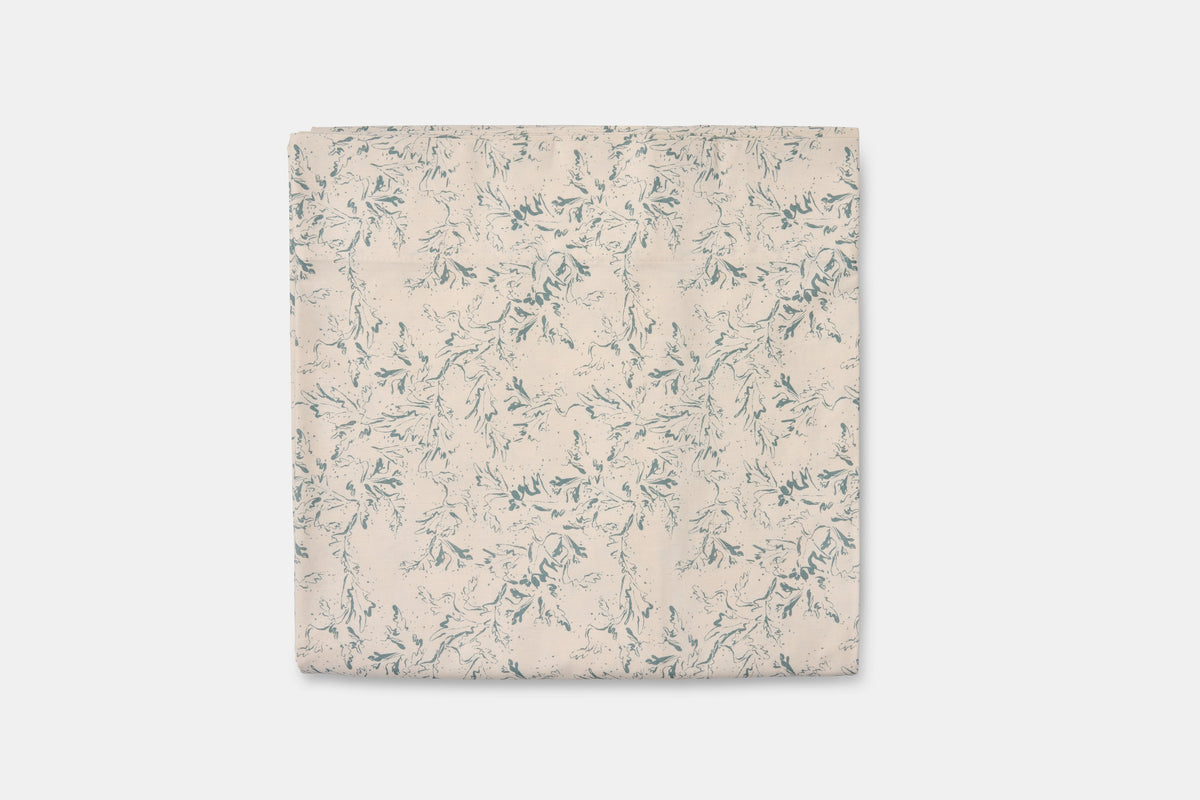 Blue botanical print cotton bed sheet set from American Blossom Linens, folded flat on a natural background.