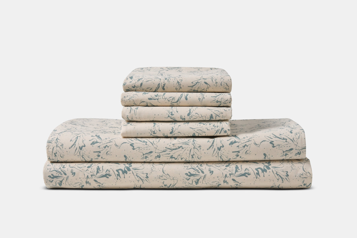 American Blossom Linens cotton bed sheet set with blue botanical print on natural background, made in the USA.