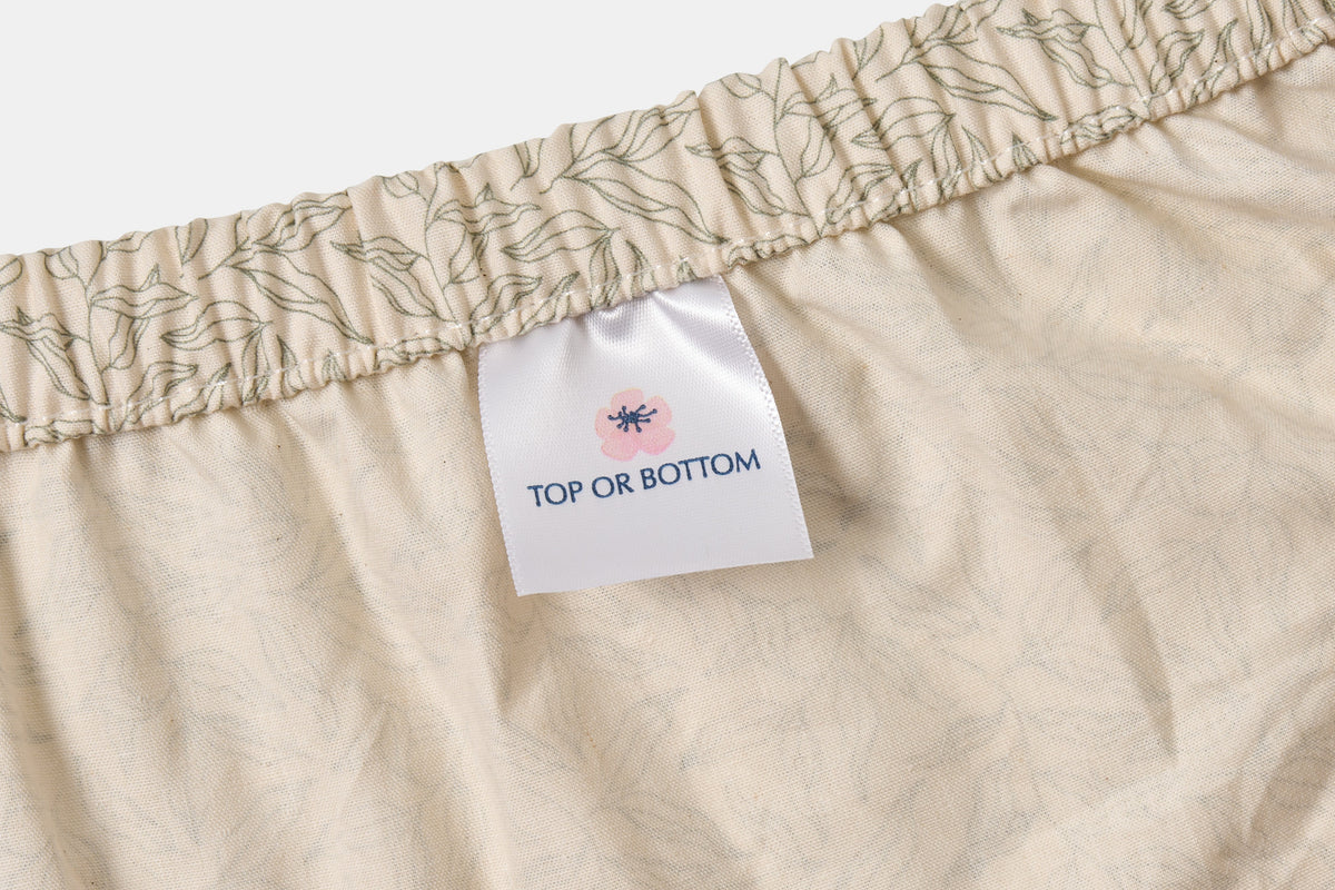 Green leaf print cotton bed sheet set by American Blossom Linens, includes fitted sheet and matching top sheet on natural background.
